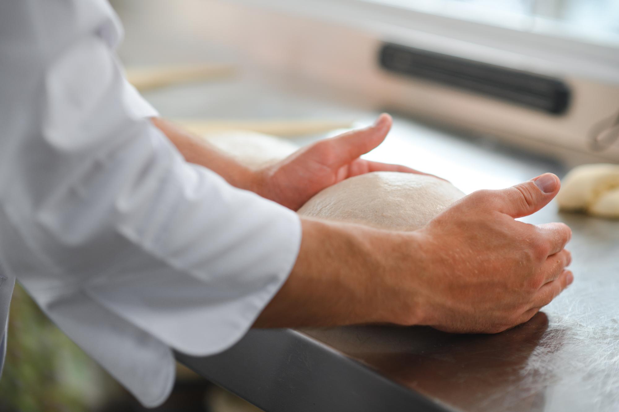 Dettaglio mani che impastano pane